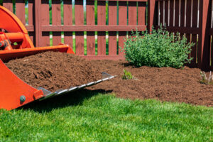 Tractor loader with wood chips or mulch and flowerbed. Lawncare, gardening and backyard landscaping concept | Quiet Village Landscaping