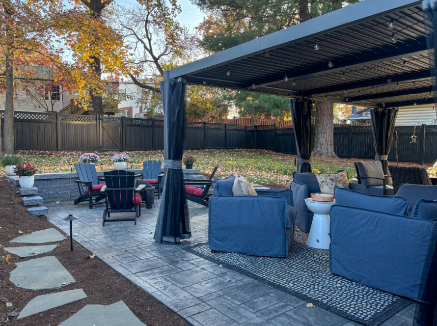 Outdoor patio area with blue cushioned seating under a canopy, string lights, and autumn leaves scattered on the ground.